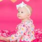 Baby in colorful outfit with candy hearts background.