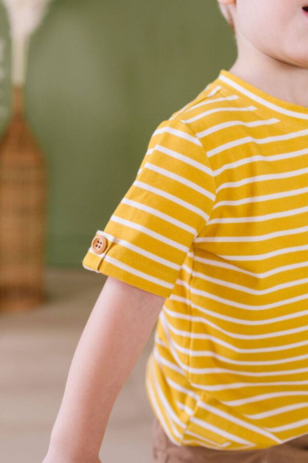 ollie jay alex tee in mustard stripe Child in yellow striped shirt, partial view