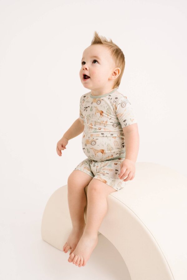 little one shop little farm bamboo shorts set Toddler sitting on a curved bench.