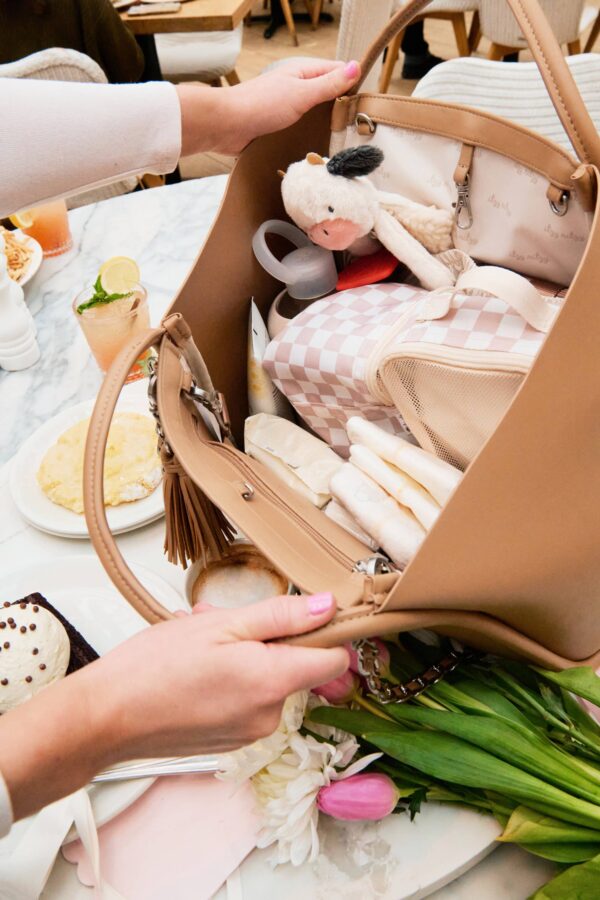 itzy ritzy *new/restocked* chai latte boss tote™ Open diaper bag on cafe table with flowers