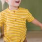 Smiling child in yellow striped shirt indoors.