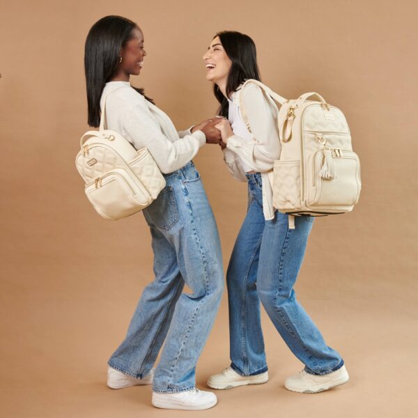 itzy ritzy milk & honey itzy mini plus™ diaper bag backpack Two women laughing with stylish backpacks.