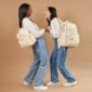 Two women laughing with stylish backpacks.