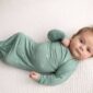 Baby in green swaddle on white blanket