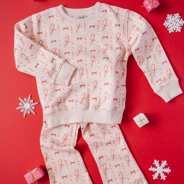 sweet wink candy cane lane christmas sweatshirt Festive candy cane print pajama set on red background.