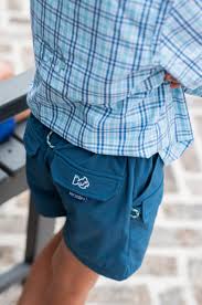 Person wearing plaid shirt and blue shorts outdoors.