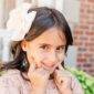 Smiling girl with bow in her hair outdoors.
