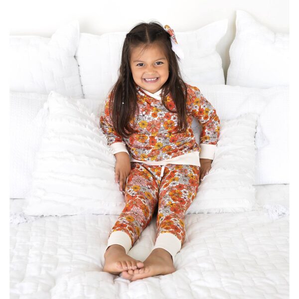 gigi and max louisa hoodie set Child in floral pajamas on bed smiling.