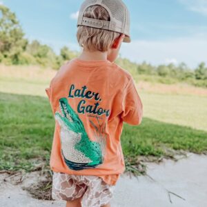 Child outdoors wearing 'Later, Gator' shirt