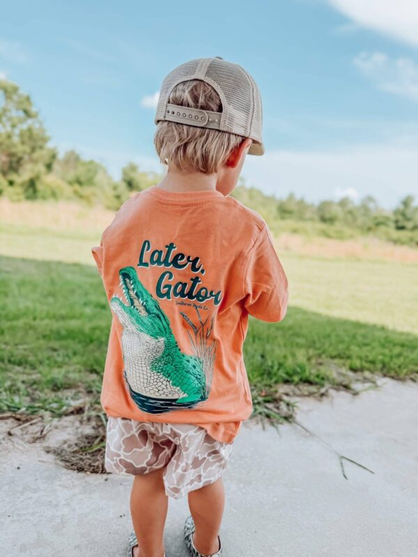 Child outdoors wearing 'Later, Gator' shirt