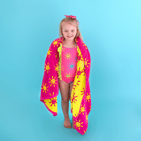gigi and max brittany smiley face tank one piece swimsuit Smiling girl in swimsuit with sun-pattern towel.