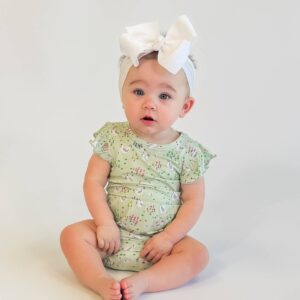 Baby in green outfit with white bow.