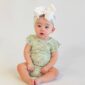 Baby in green outfit with white bow.