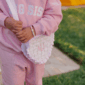 Child in pink outfit holding a frilly bag