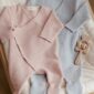 Pink and blue baby onesies with rattle.