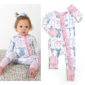 Baby wearing bow-patterned romper on patterned rug.