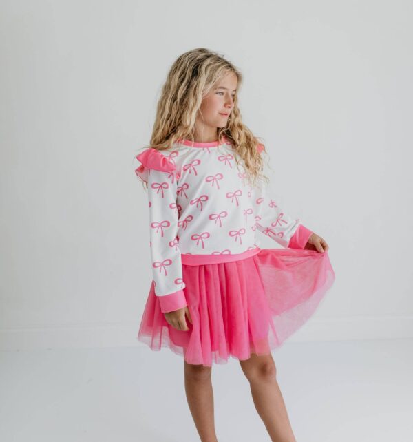 product Girl in pink bow-patterned outfit poses confidently.