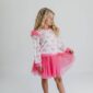 Girl in pink bow-patterned outfit poses confidently.