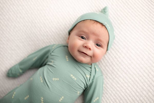 three little tots arrow print knotted newborn baby gown pajamas Smiling baby in green outfit on white blanket.