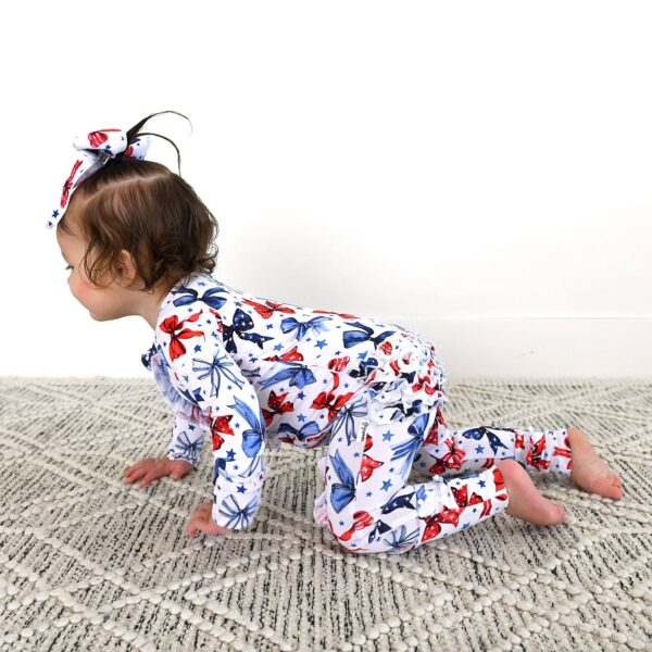 gigi and max eleanor bow clip bow 4th of july hair accessory Baby in patriotic star-patterned pajamas crawling on carpet.