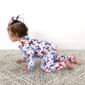 Baby in patriotic star-patterned pajamas crawling on carpet.