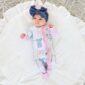 Baby in bow outfit on white blanket.