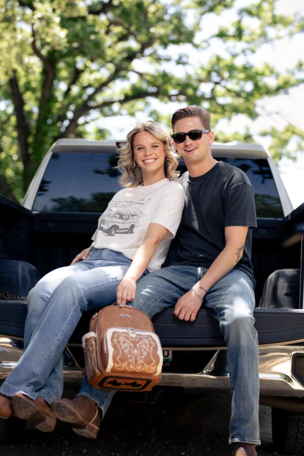 itzy ritzy nash mini plus™ backpack diaper bag Smiling couple sitting on a truck tailgate outdoors.