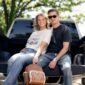 Smiling couple sitting on a truck tailgate outdoors.