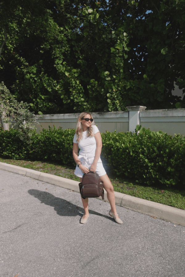 itzy ritzy *new* espresso itzy mini plus™ Woman in sunglasses with backpack on sunny day.