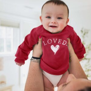 Smiling baby in red "Loved" sweater.
