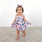 Child in butterfly dress and matching bow smiling.