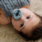Baby with pacifier laying on soft blanket