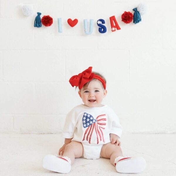 Baby in patriotic outfit with 'I ❤️ USA' banner.
