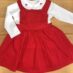 Red dress with white collar on wood surface.