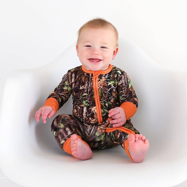 gigi and max hunter camo zip sleepies little bamboo baby outfit Smiling baby in camo onesie sitting on chair.