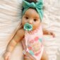 Baby with pacifier and headband on blanket.