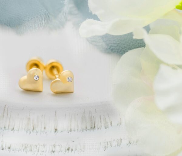cherished moments kids 14k gold puff heart earrings Gold heart earrings with diamonds on soft fabric.