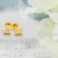 Gold heart earrings with diamonds on soft fabric.