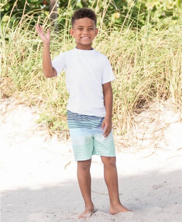 Smiling boy waving on a sunny beach day.