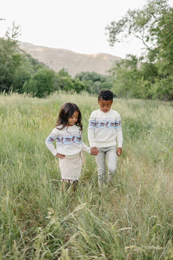 velvet fawn rylee sweater mallards Children walking hand in hand through grassy field.