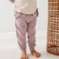 Child wearing purple pants, barefoot on wooden floor