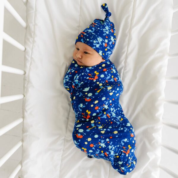 little sleepies blue paint party swaddle + hat set Newborn in blue swaddle with colorful splatter design.