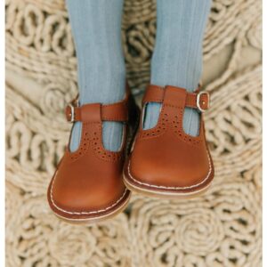 Brown leather children's shoes on braided rug