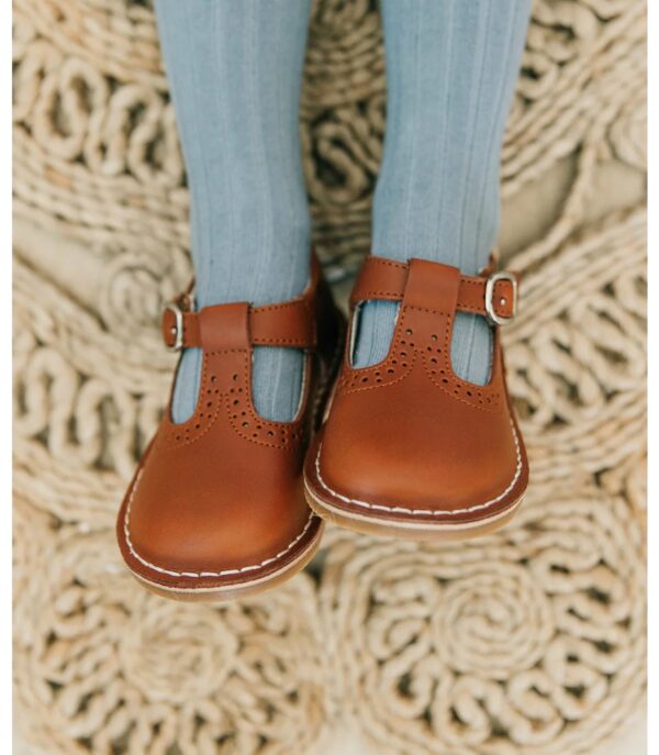 Brown leather children's shoes on braided rug