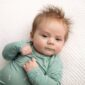 Cute baby in green onesie on blanket