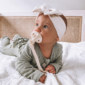 Baby with pacifier lying on a bed.