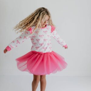 Girl twirling in pink bow-pattern dress