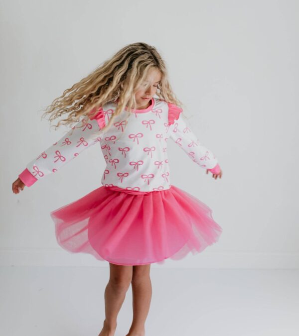 product Girl twirling in pink bow-pattern dress