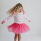 Girl twirling in pink bow-pattern dress