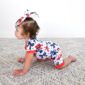 Baby in patriotic outfit crawling on carpet.